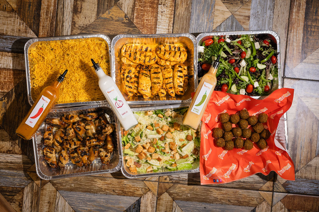 Catering spread with yellow rice, grilled chicken, and Caesar salad