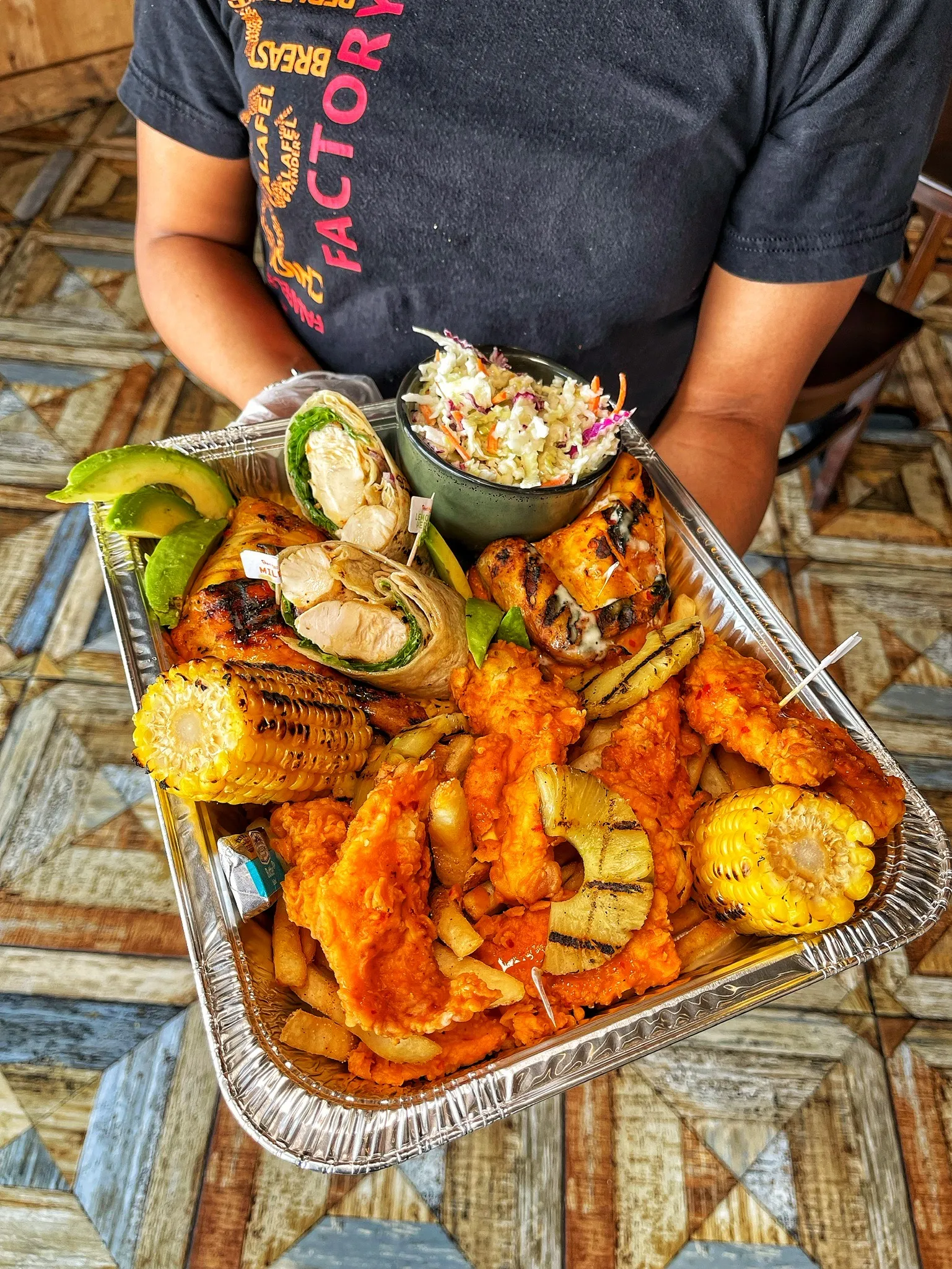Staff holding catering tray with fried chicken wraps and milkshake