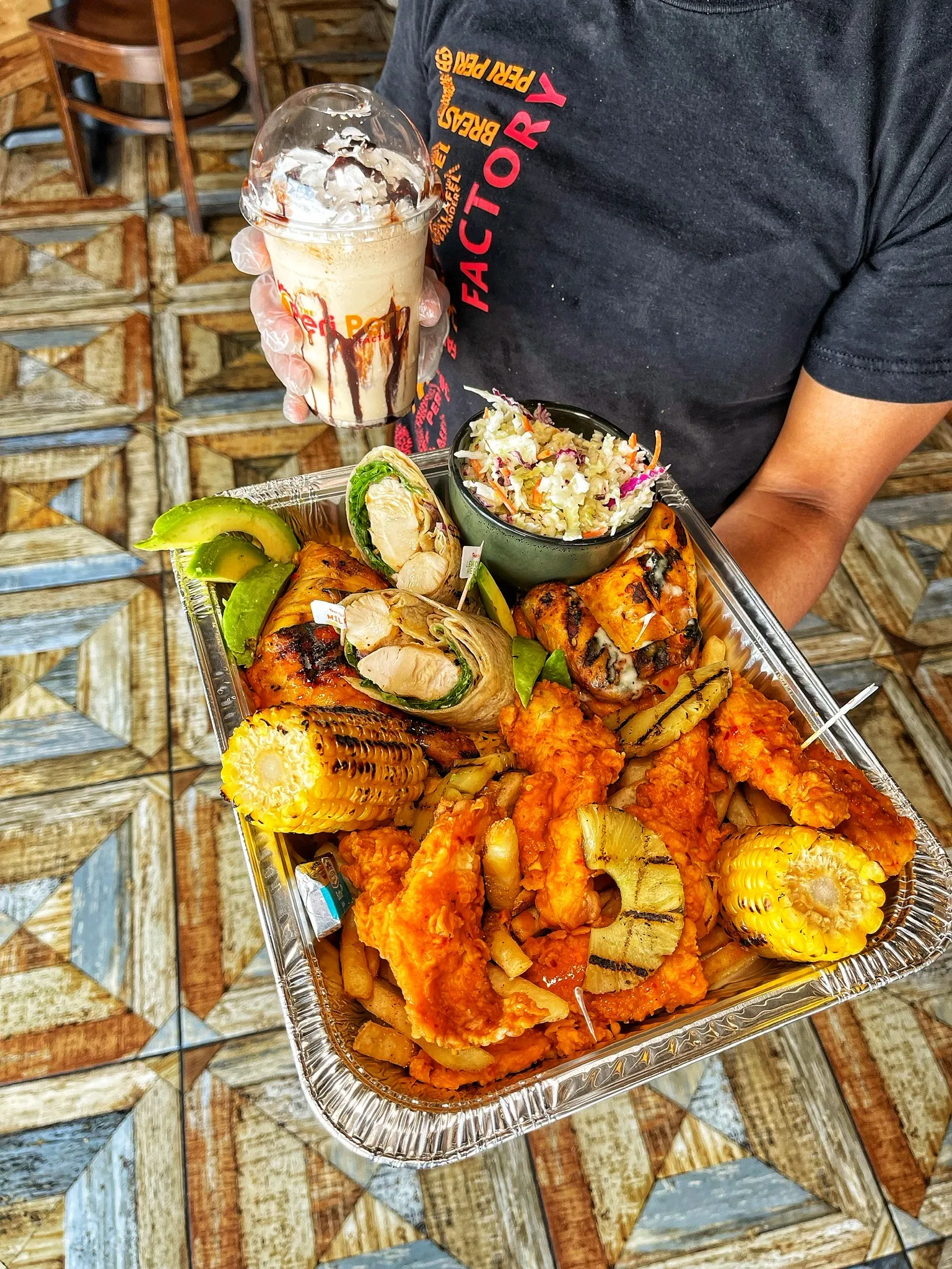 Staff holding catering tray with food spread and milkshake