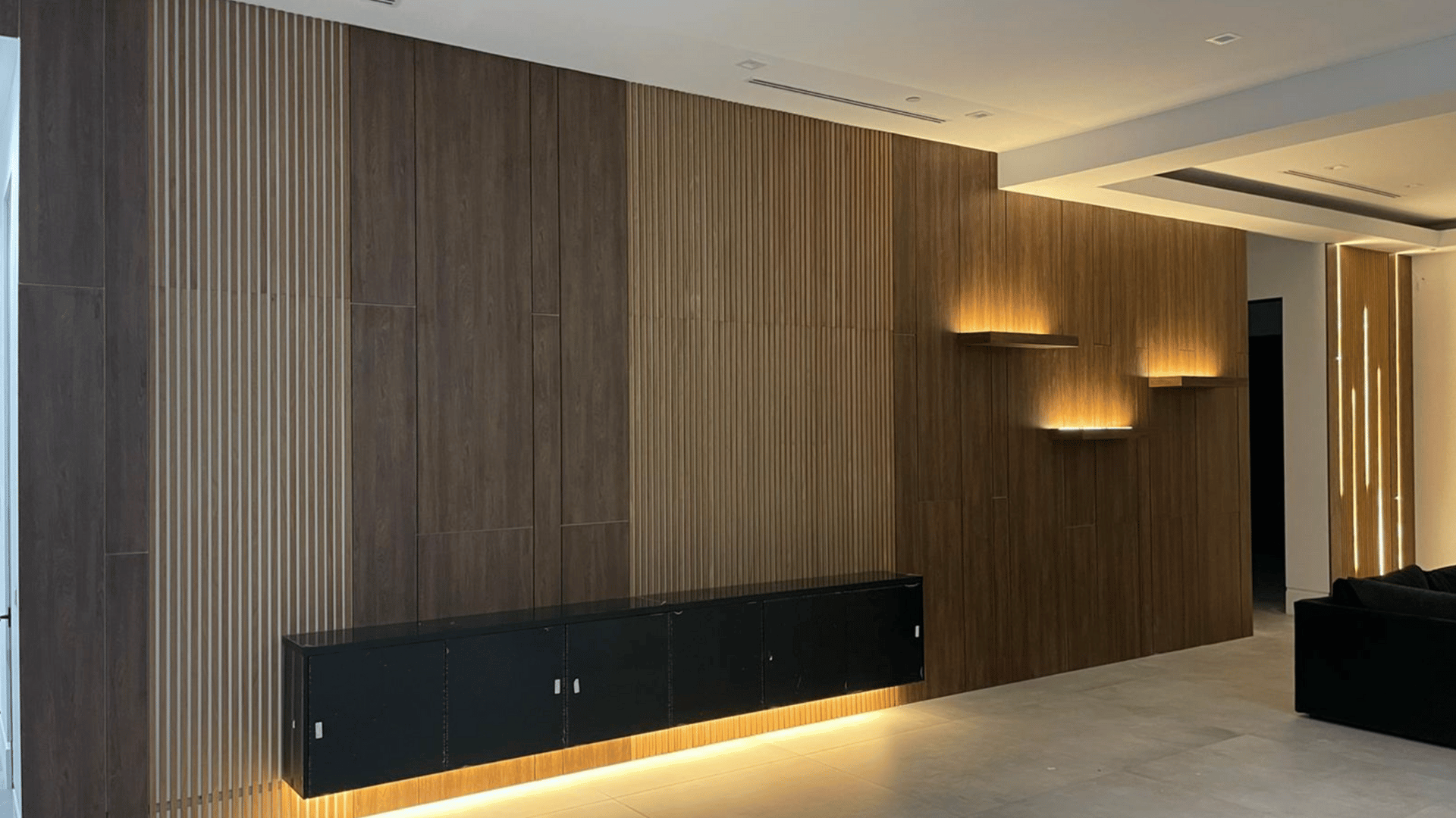 nterior living room with a modern wood-paneled wall, integrated lighting, and minimalist design.