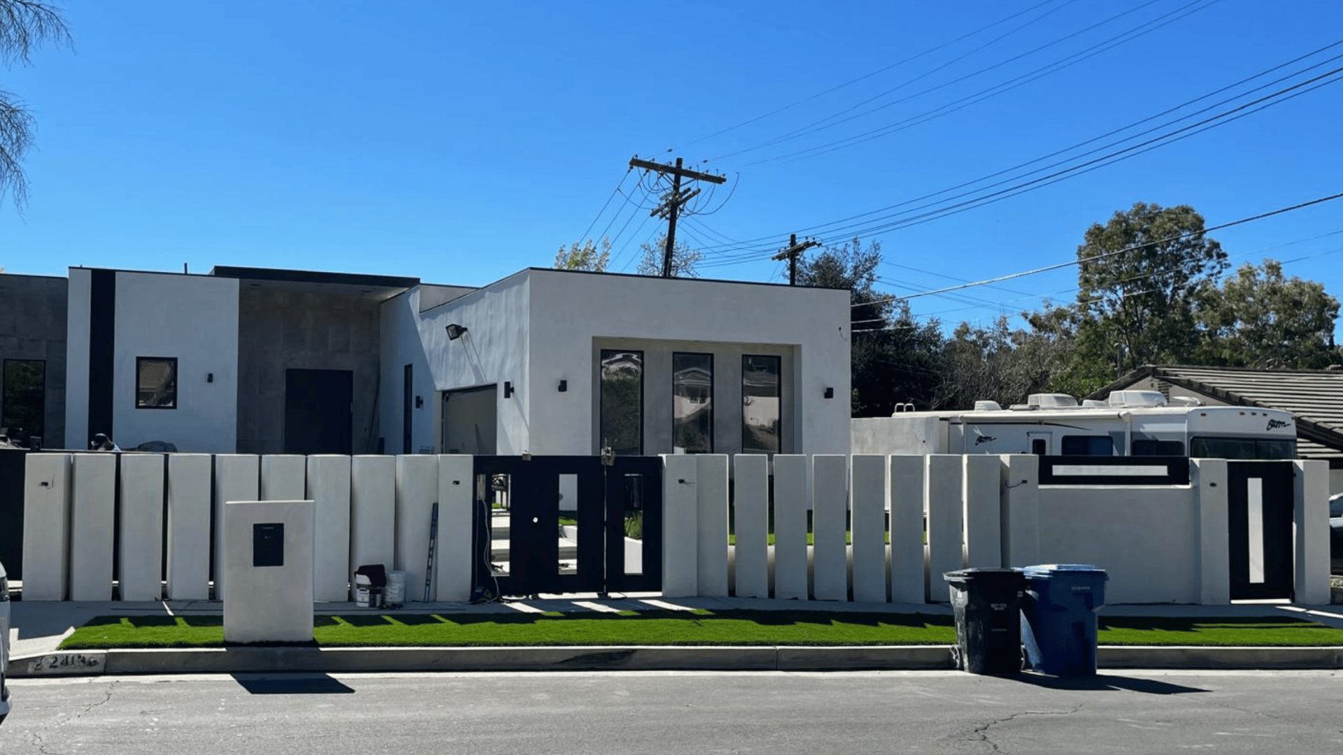 Modern white exterior home with a minimalist fence, black and white color scheme, and clean lines.