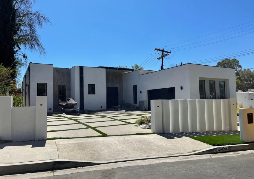  Modern minimalist home exterior with a concrete driveway, large front yard, and unique fence design.