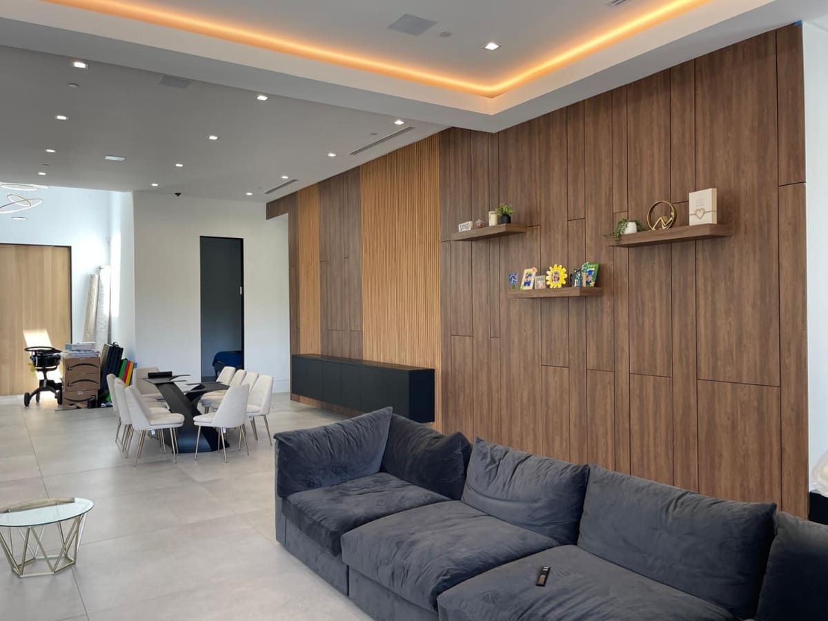 Open-concept living and dining area with wood-paneled walls, modern furniture, and recessed lighting for a sleek design.