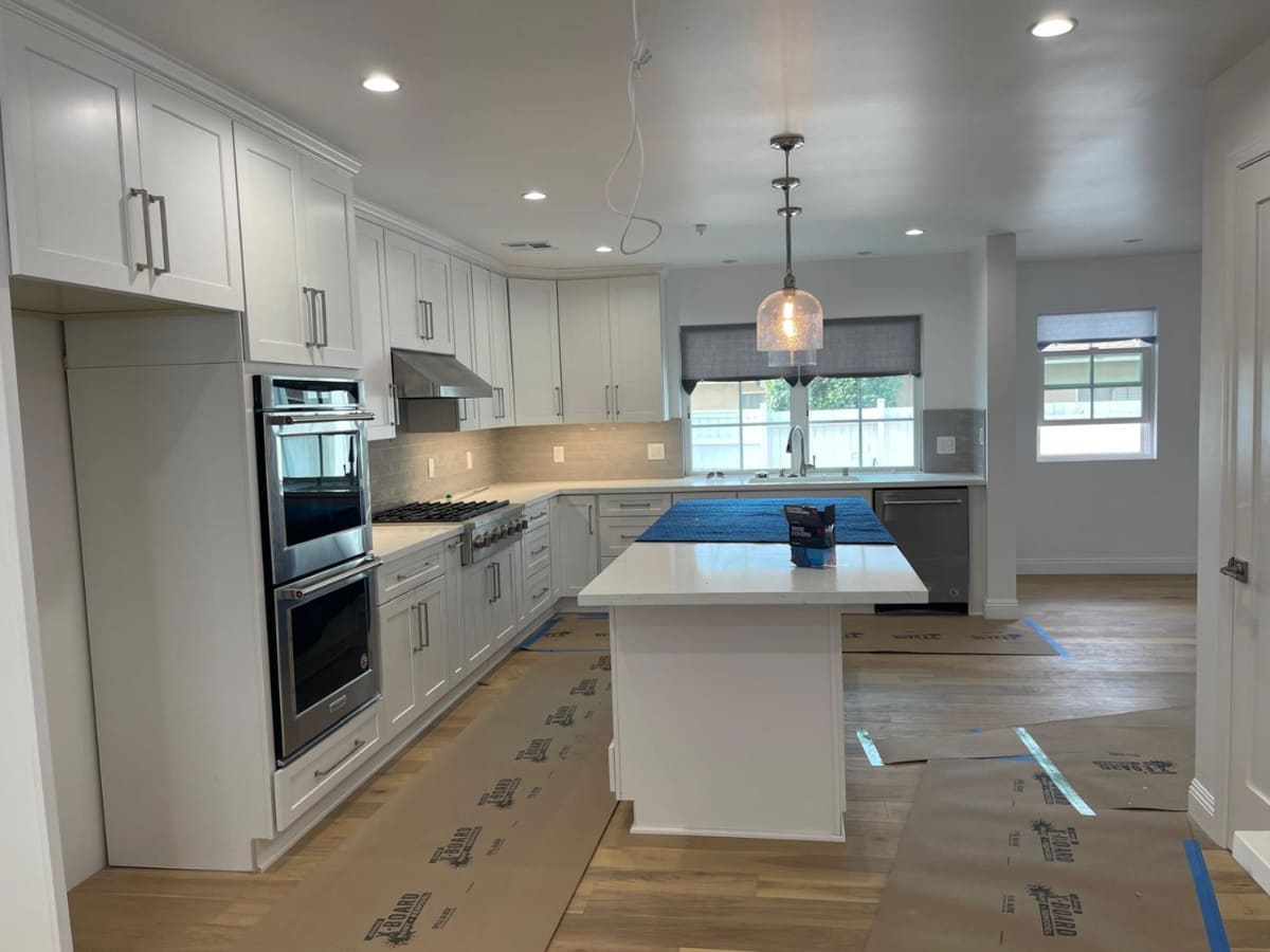 Spacious kitchen with white cabinetry, stainless steel appliances, and a large central island in a modern home.