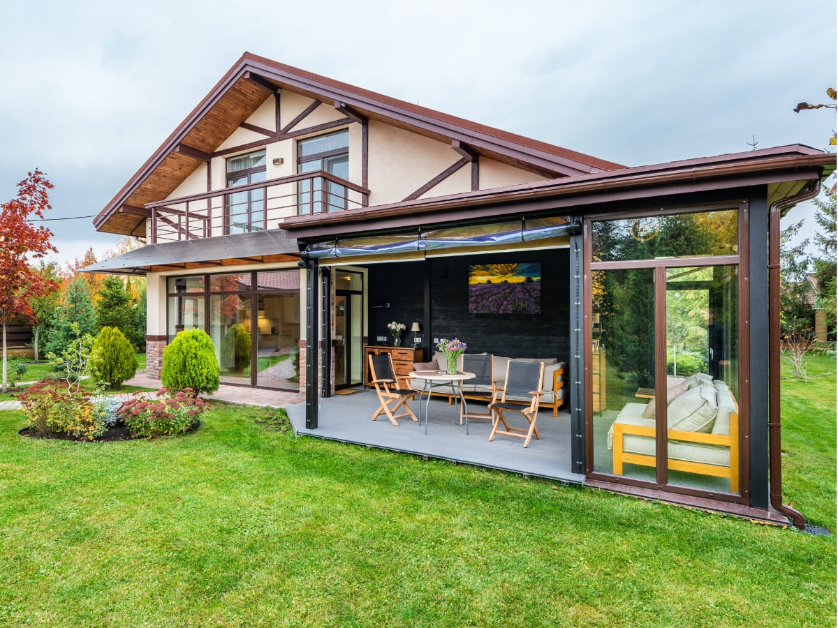 Modern home with an outdoor patio area, featuring a covered dining space and large glass sliding doors opening to a well-manicured lawn.