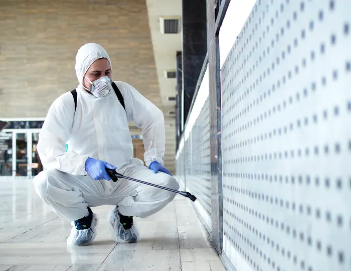 Cleaner in protective suit disinfecting a medical facility