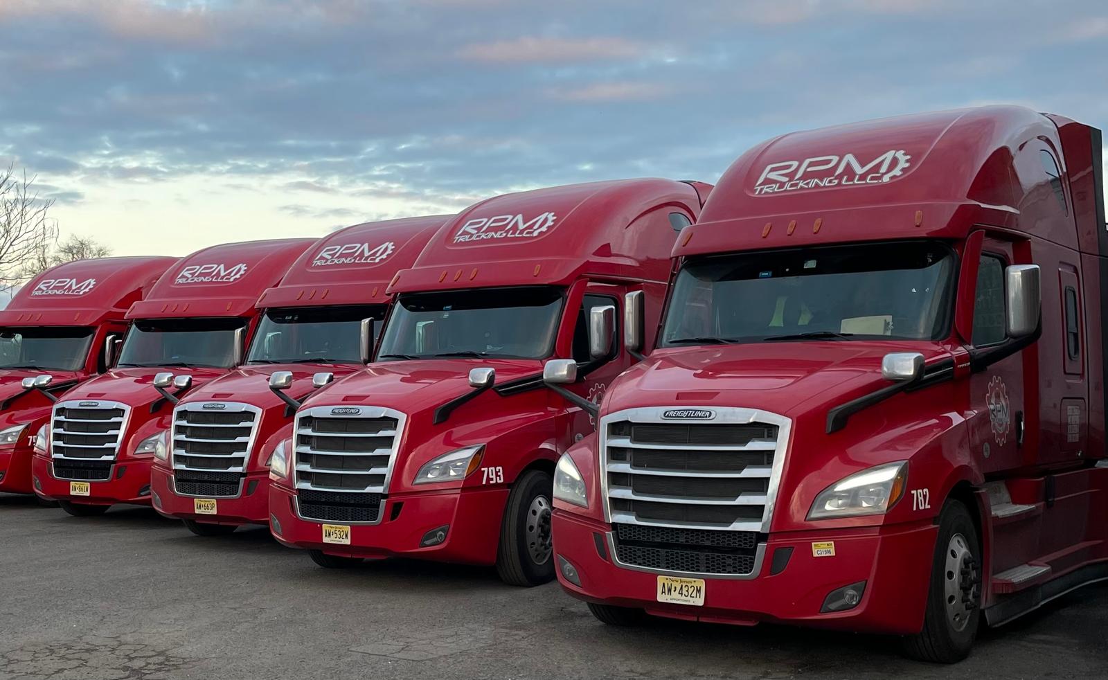 Red RPM Trucking semi trucks lined up in the yard at dusk
