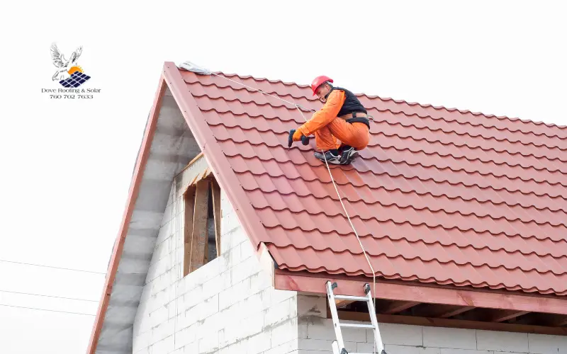 Roofer secured by a safety rope working on a steep red clay tile roof