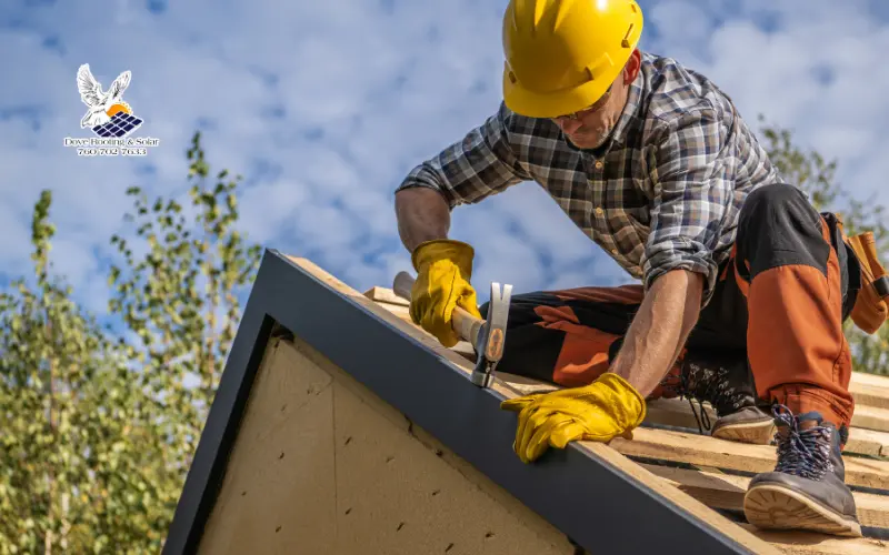 Roofer in yellow gloves nailing wood roof decking on a new construction frame