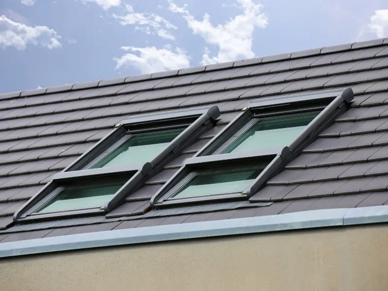 Dark grey tile roof with two vented skylight roof windows