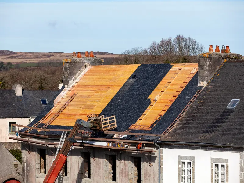 Roof under reconstruction showing bare decking and slate tile sections
