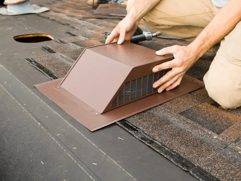 Roofer installing a roof vent during a shingle roof replacement