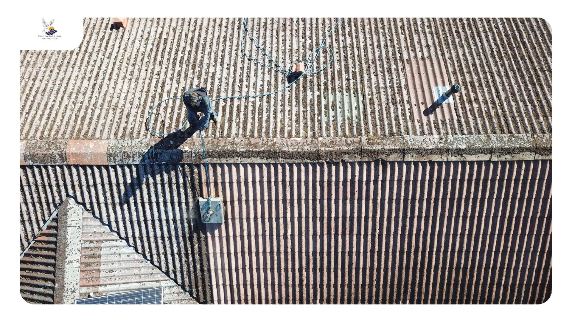 Roofer clearing packed sand and palm litter from a tile roof valley — roof cleaning Desert Hot Springs CA
