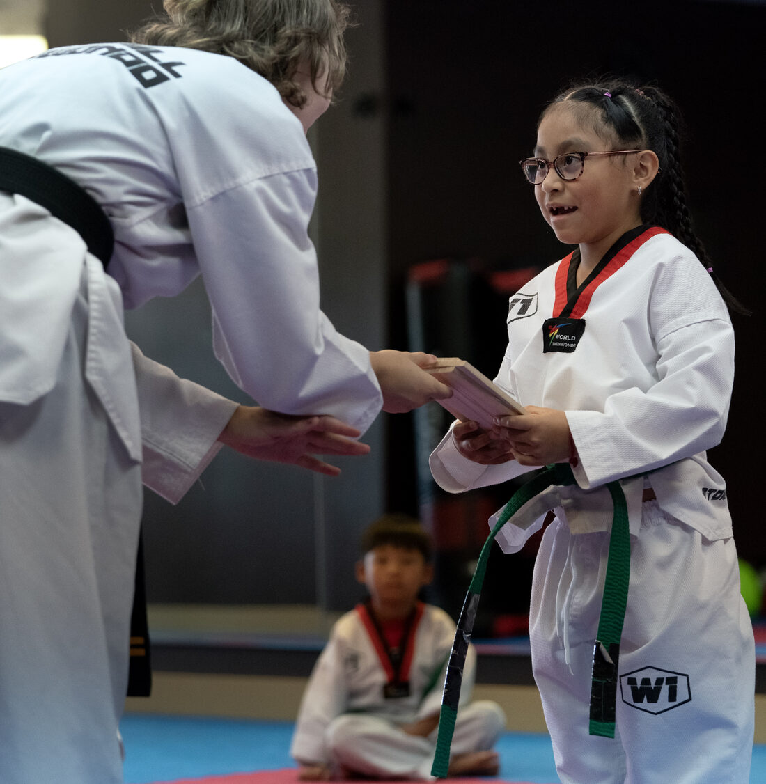A black belt instructor presenting a student with her testing board at W1 Taekwondo