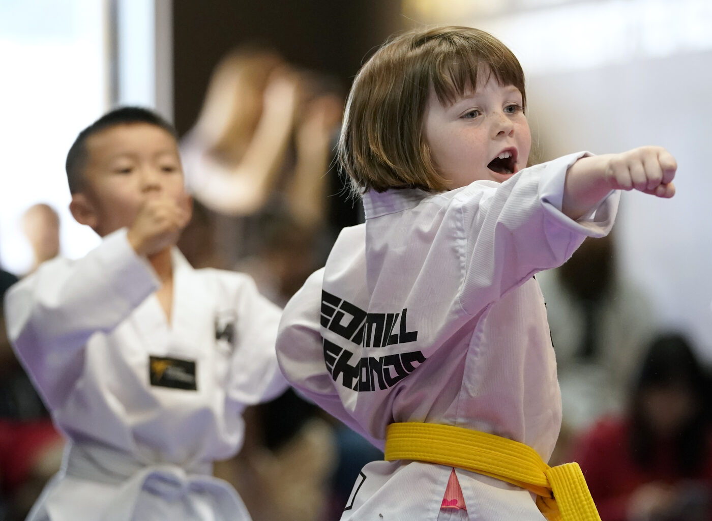 W1 Taekwondo student mid-strike in competition, focused and in motion
