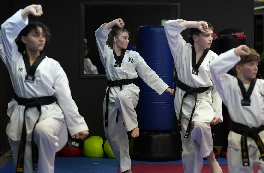 A black belt instructor leading teen students through a drill at the bag
