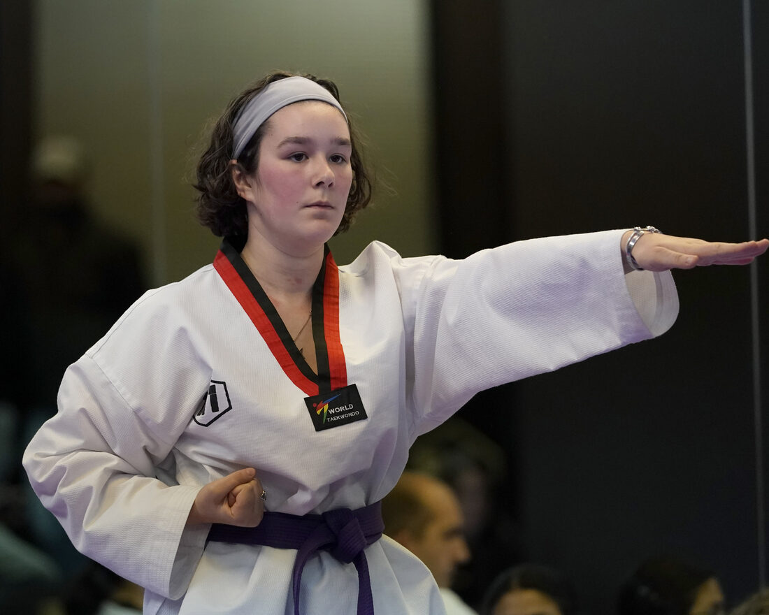 A focused teen student mid technique in competition uniform at W1 Taekwondo