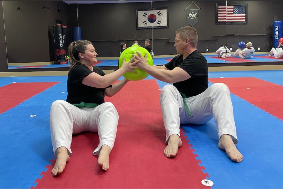 Two adult students doing a partner conditioning drill with a medicine ball at W1 Taekwondo
