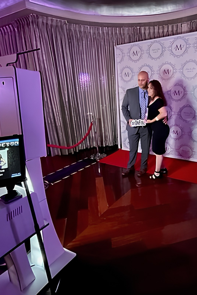 Couple posing at a step-and-repeat photo booth backdrop