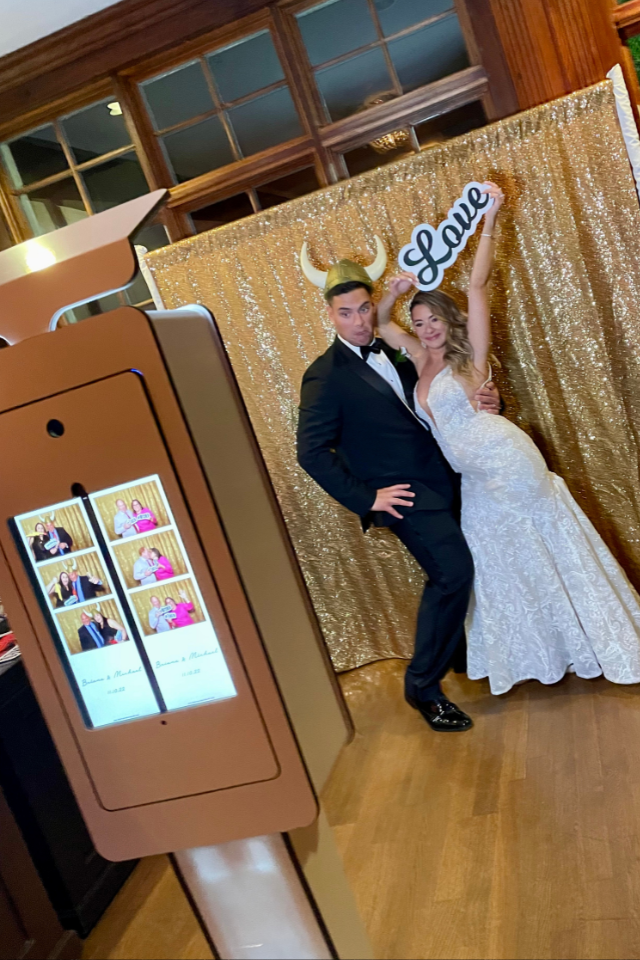 Couple posing on a red carpet at a monogram photo booth backdrop