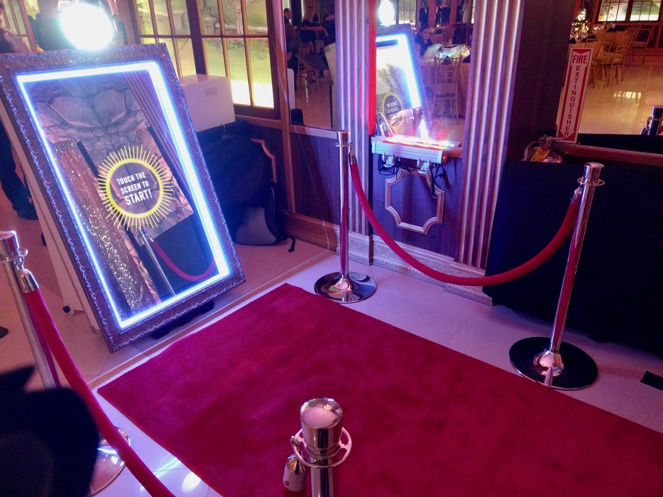 Interactive mirror photo booth with red carpet and stanchions