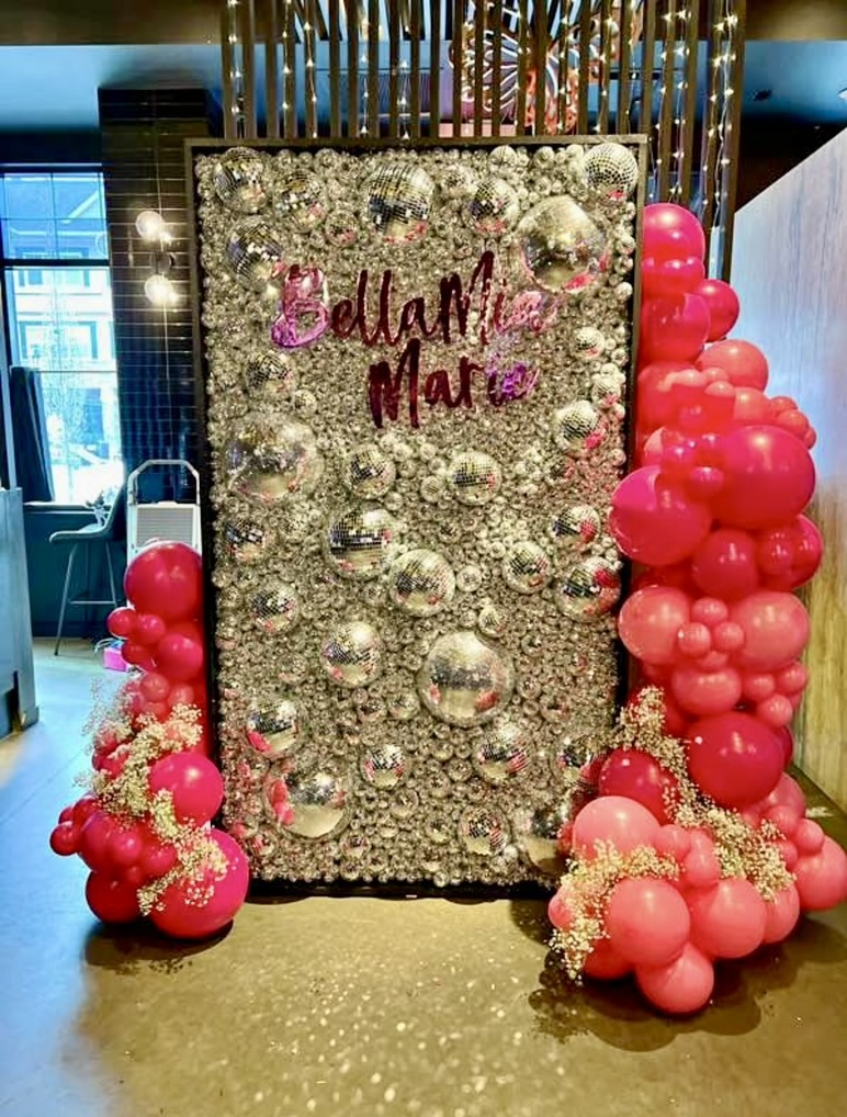 Disco ball wall with pink balloon garlands and a custom name plate