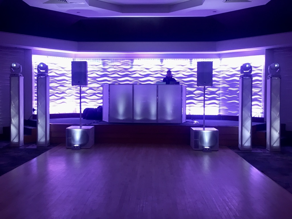 Four tower lights around the DJ booth in purple light