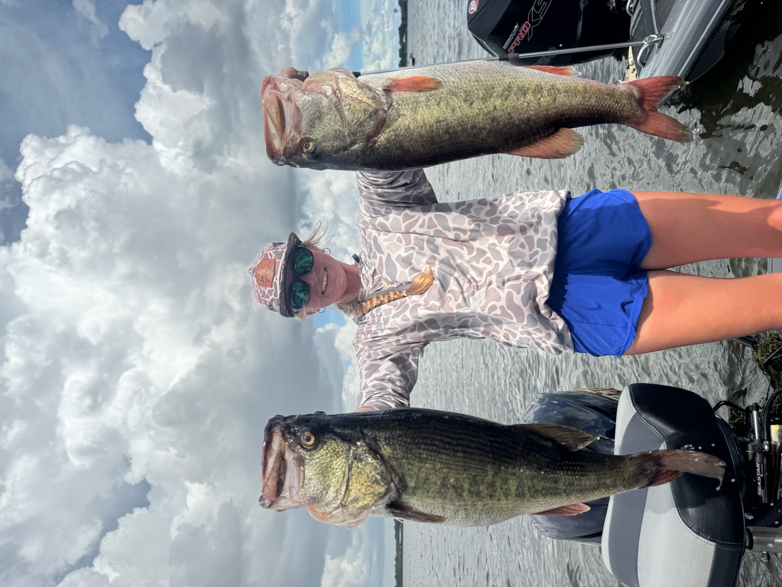 Ella Ready holding the two large bass on the water.