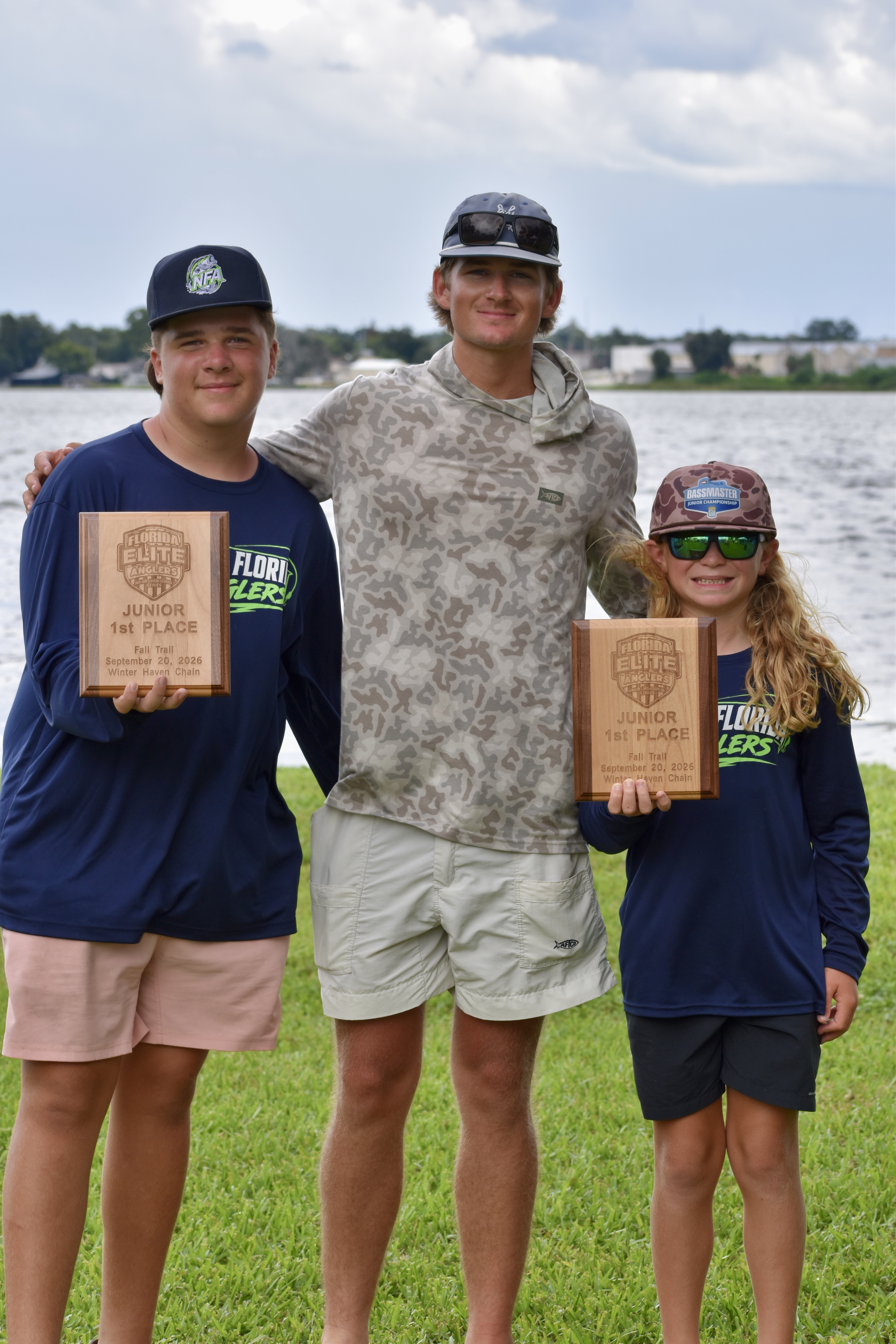 Fisher Holloway and Brycen Moriarty holding their Fall Trail #1 plaques with the third person between them.