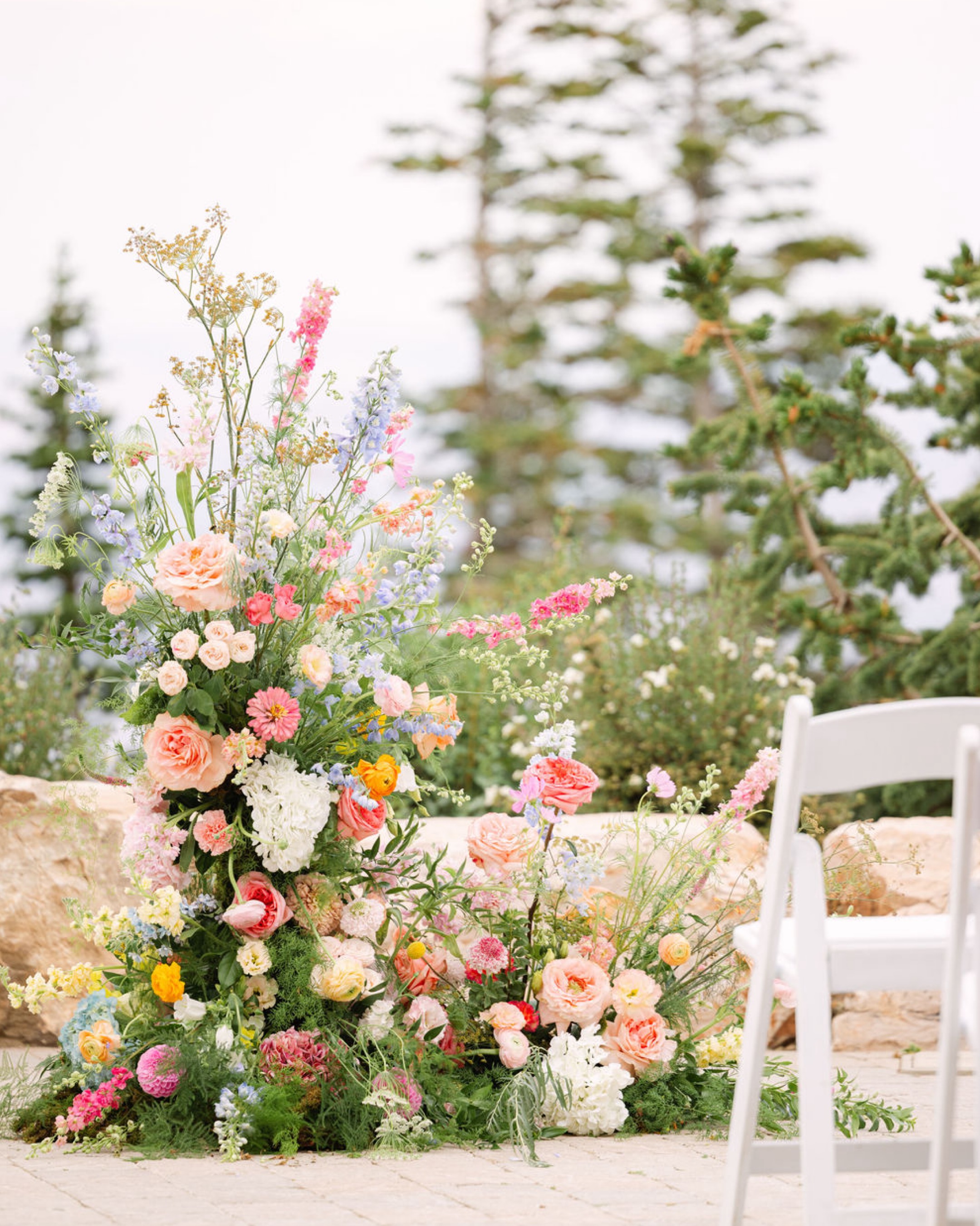 Tall wildflower arrangement beside white ceremony chairs