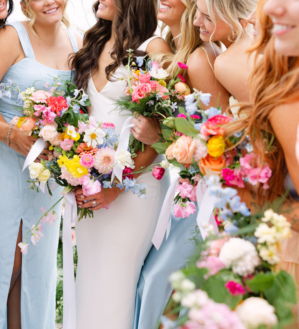 Bridesmaids in powder blue holding colorful garden bouquets