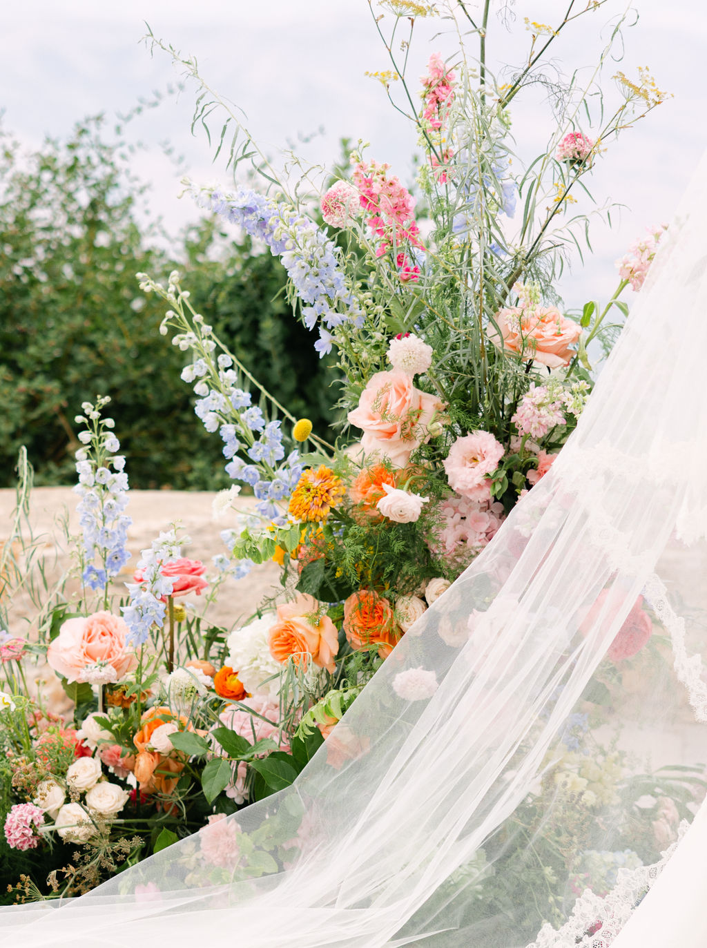 Delphinium and garden roses framing a flowing bridal veil