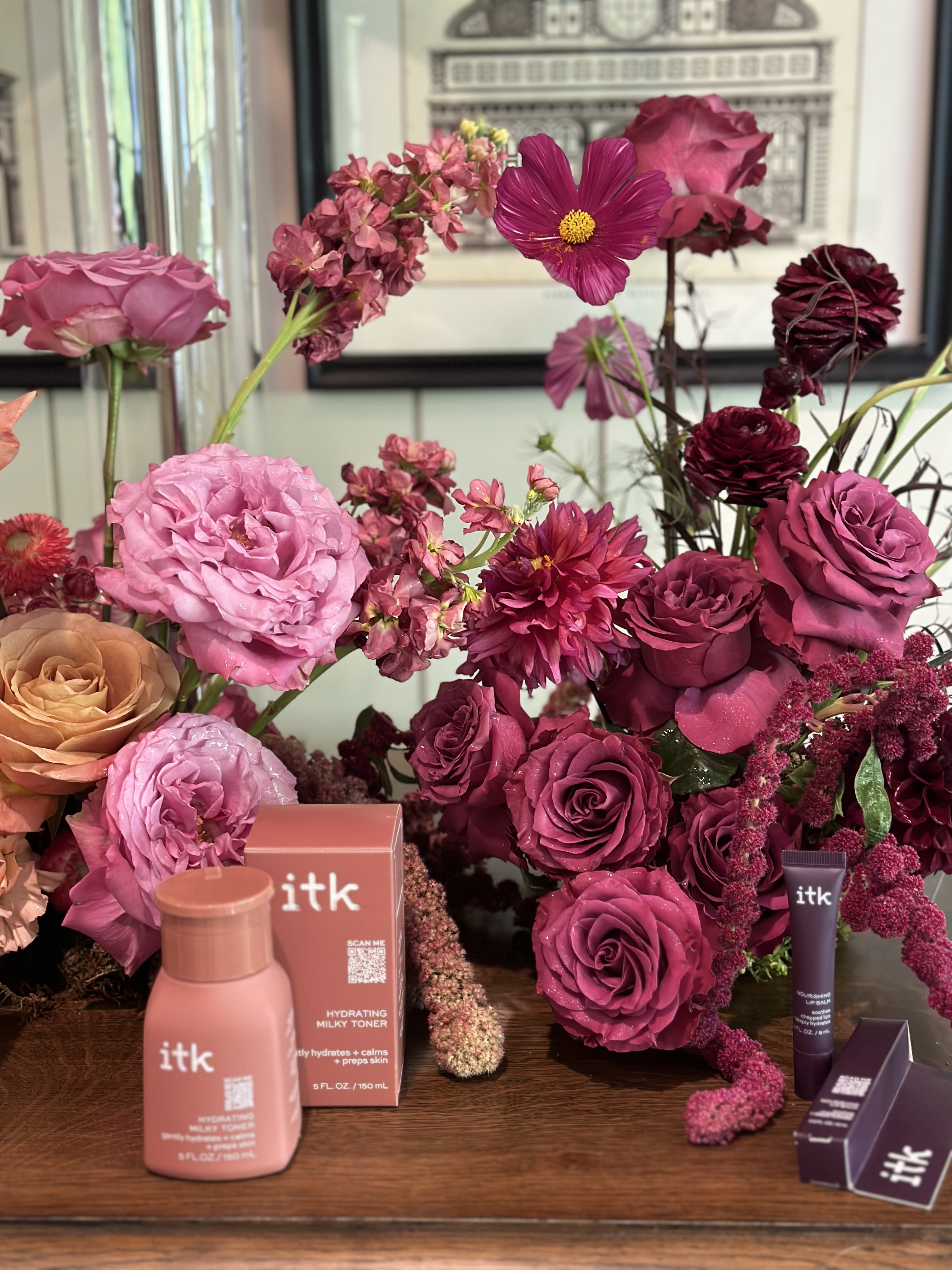 Lush berry and magenta rose arrangement styled around beauty products for a brand activation
