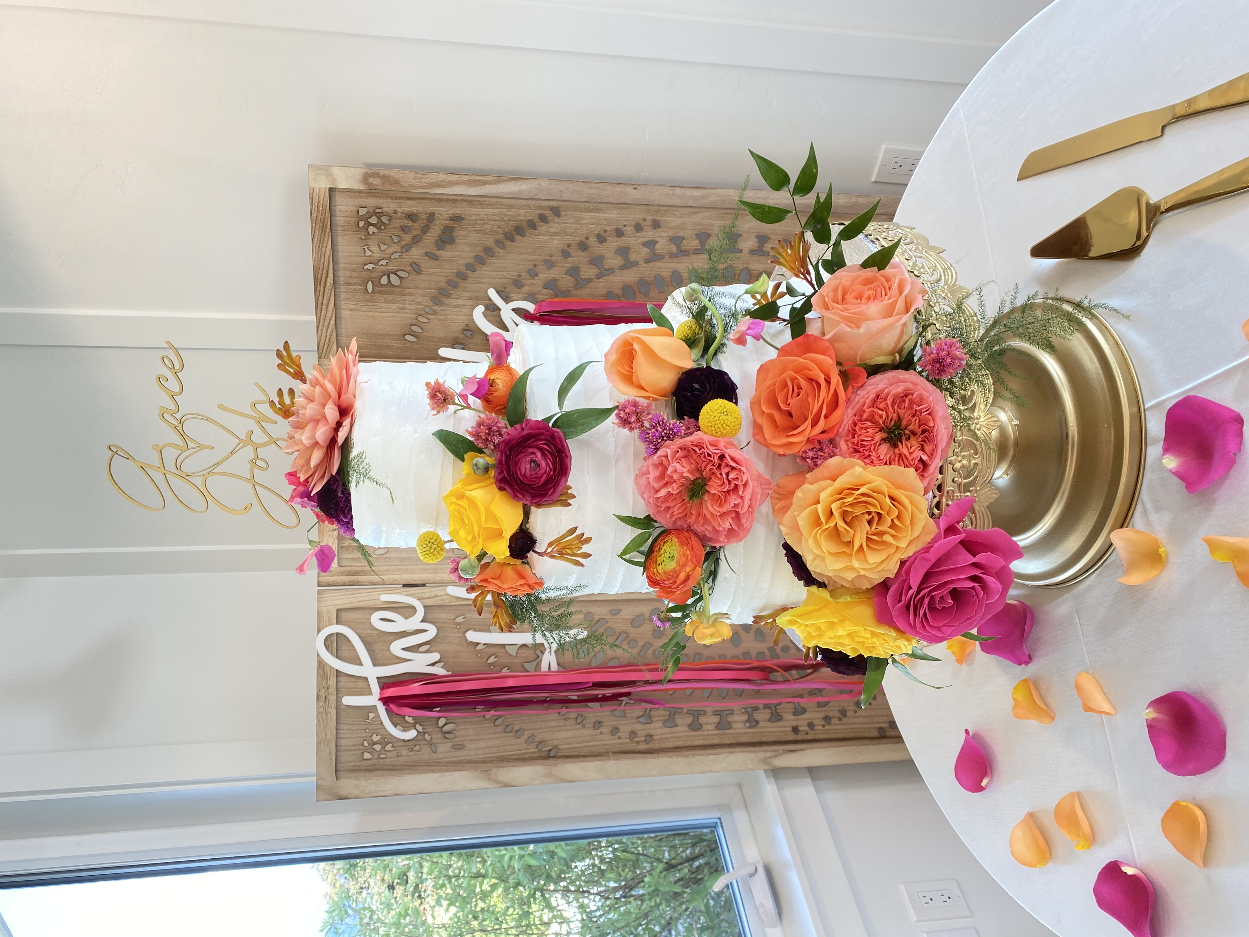 Tiered wedding cake dressed in orange and pink blooms