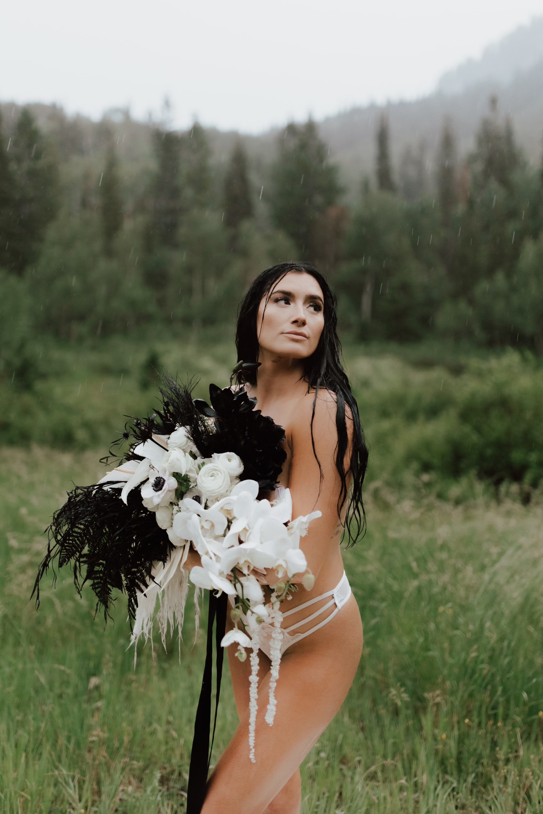 Bride in a meadow holding a black and white bouquet