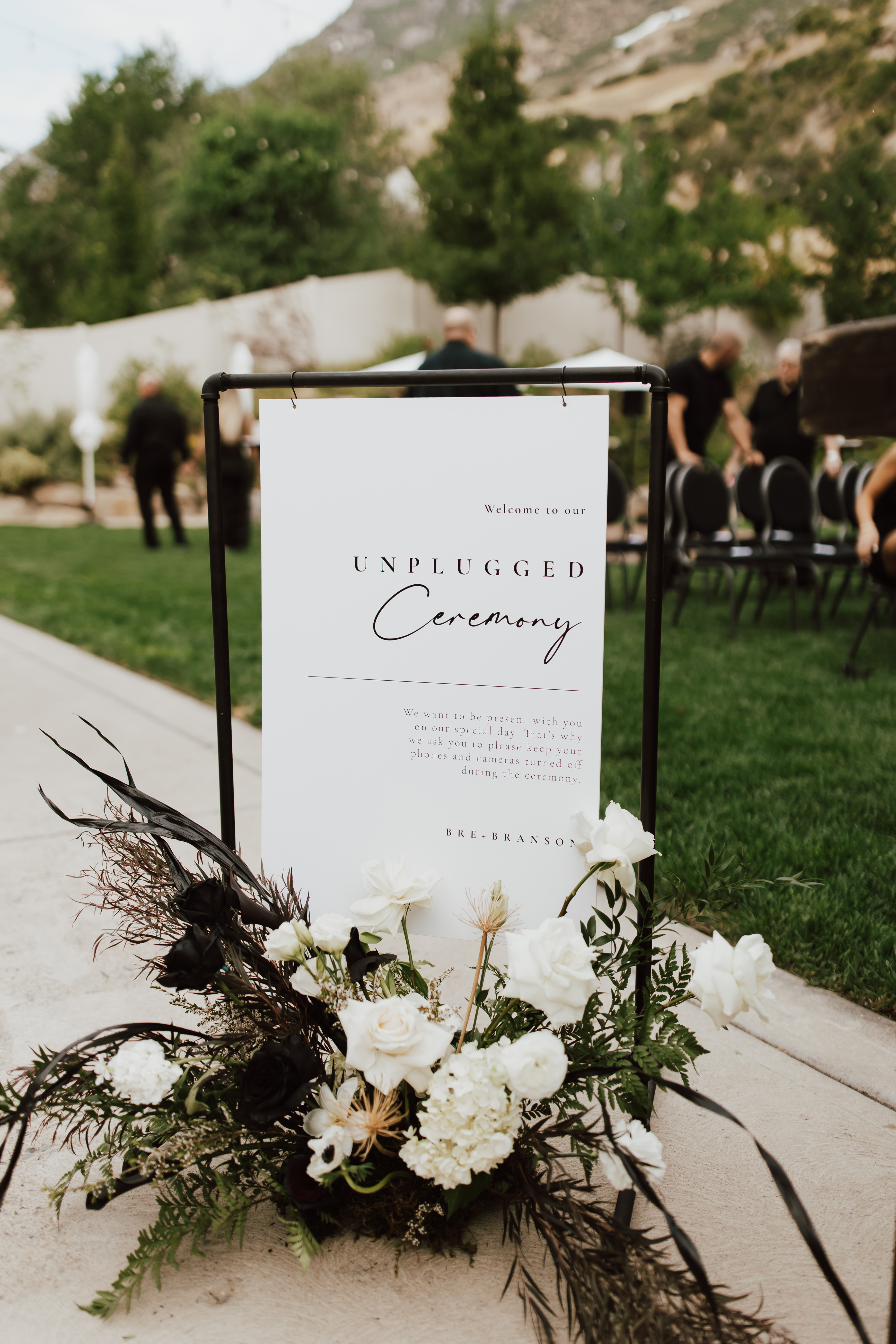 Ceremony welcome sign anchored by black and ivory florals