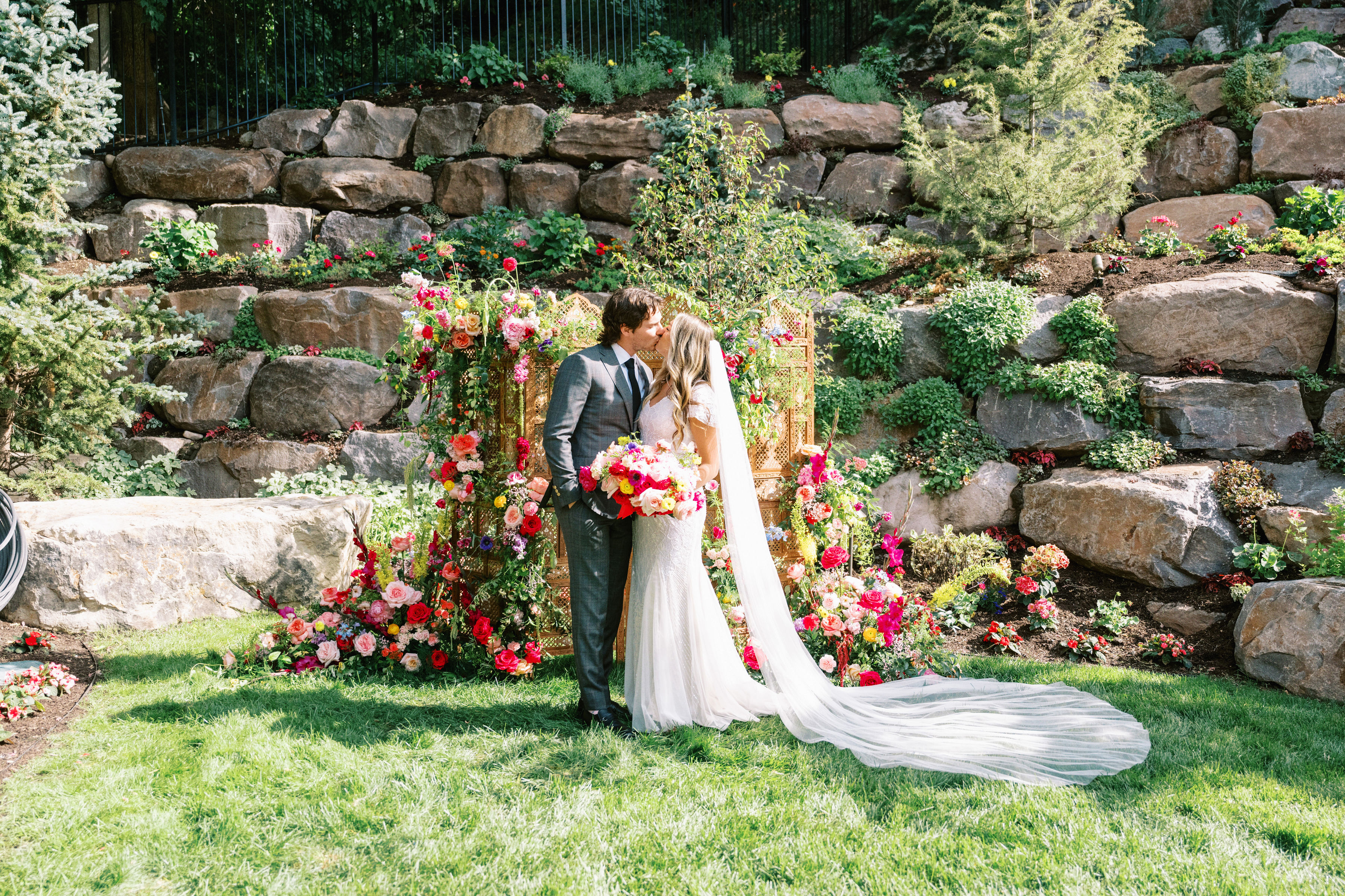 Couple at a floral-framed altar in front of a stone wall