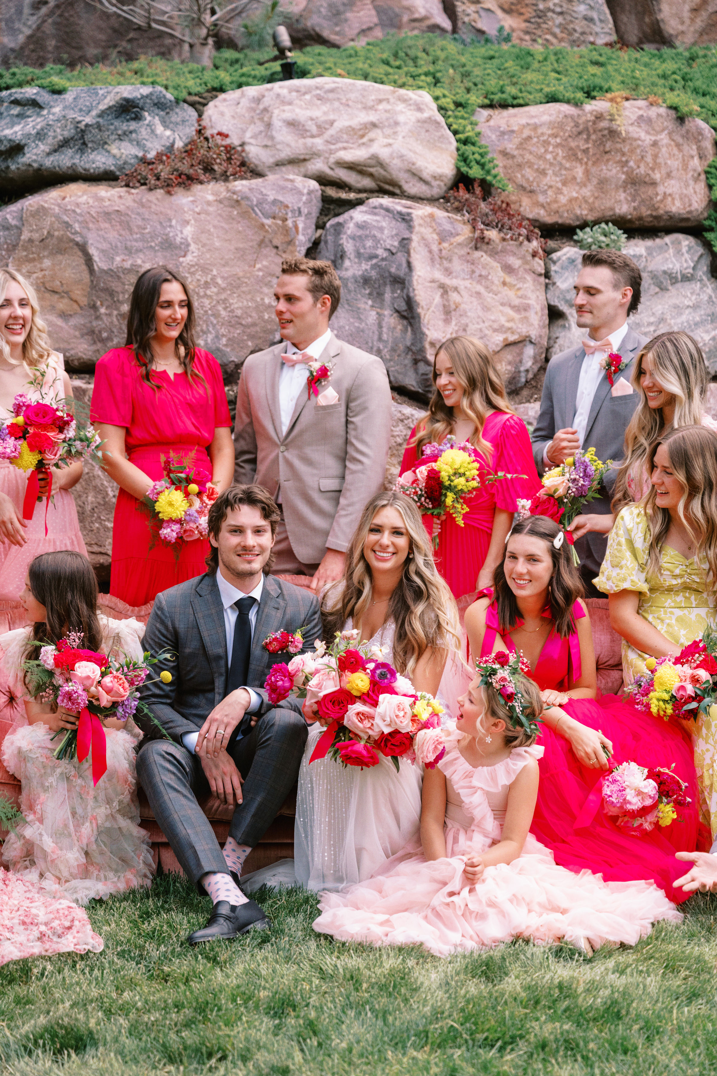 Wedding party in pink and red on a stone garden wall