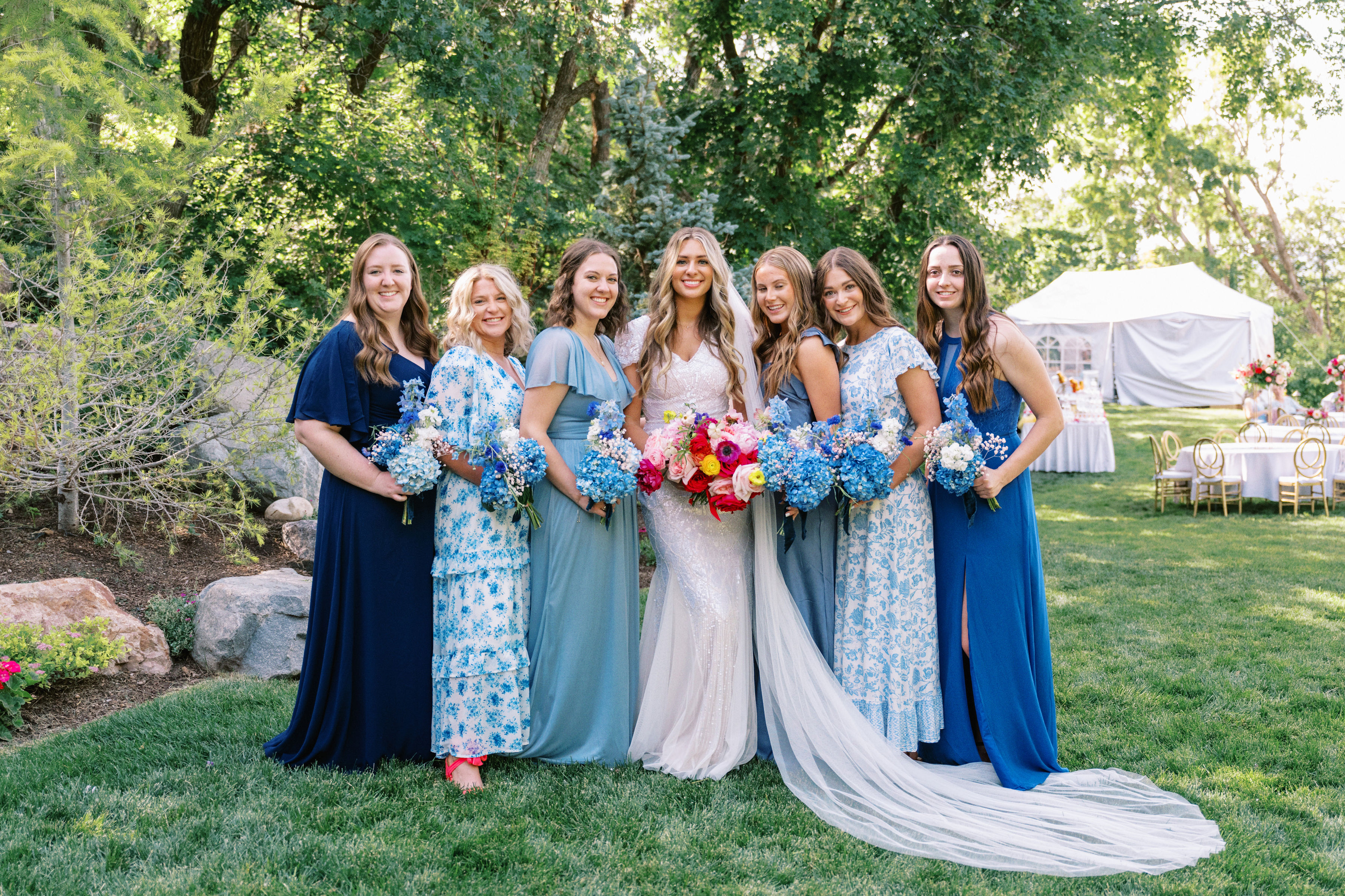 Bride with bridesmaids in shades of blue on the lawn