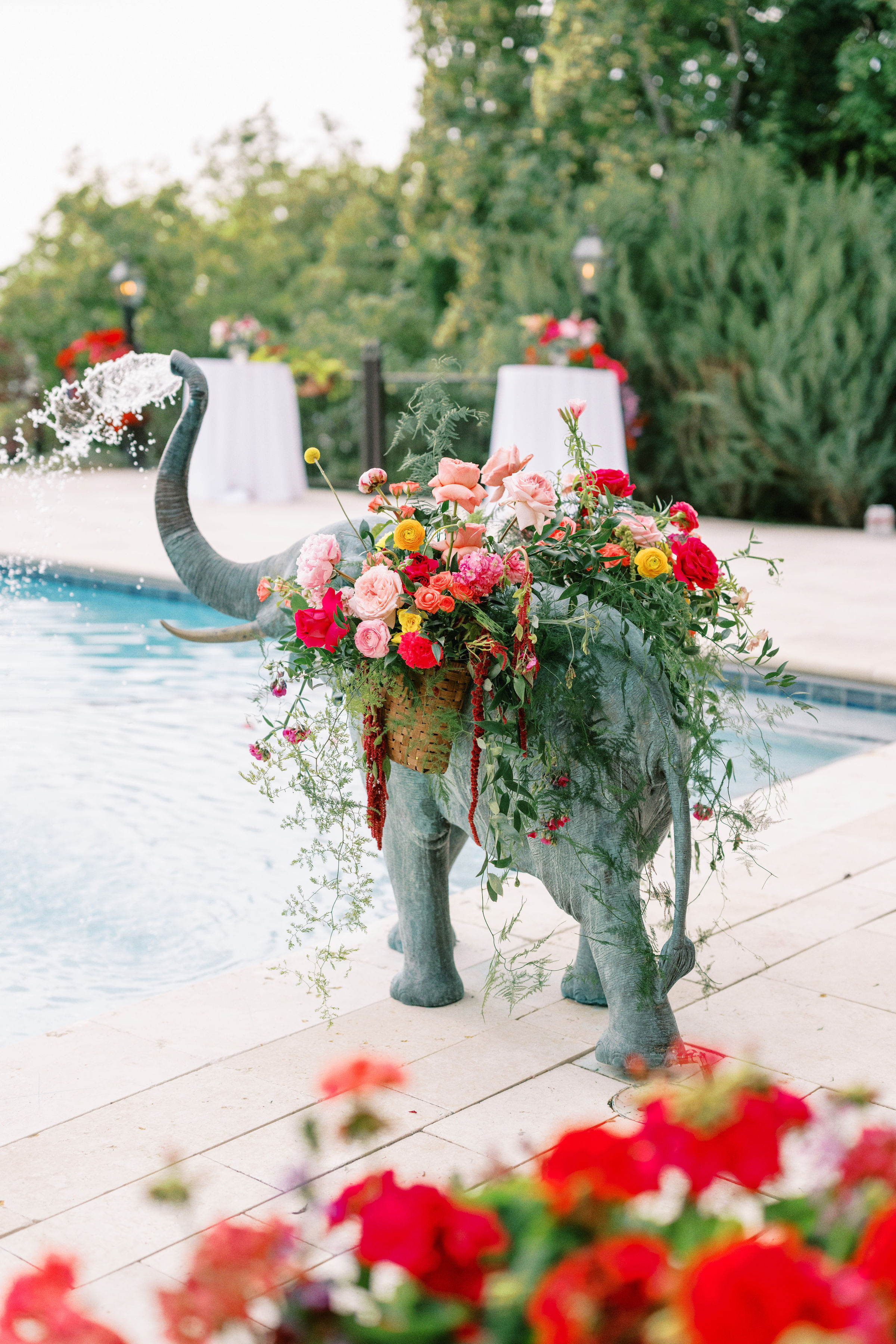 Elephant sculpture crowned with red florals beside the pool at a 1920s Italian inspired wedding