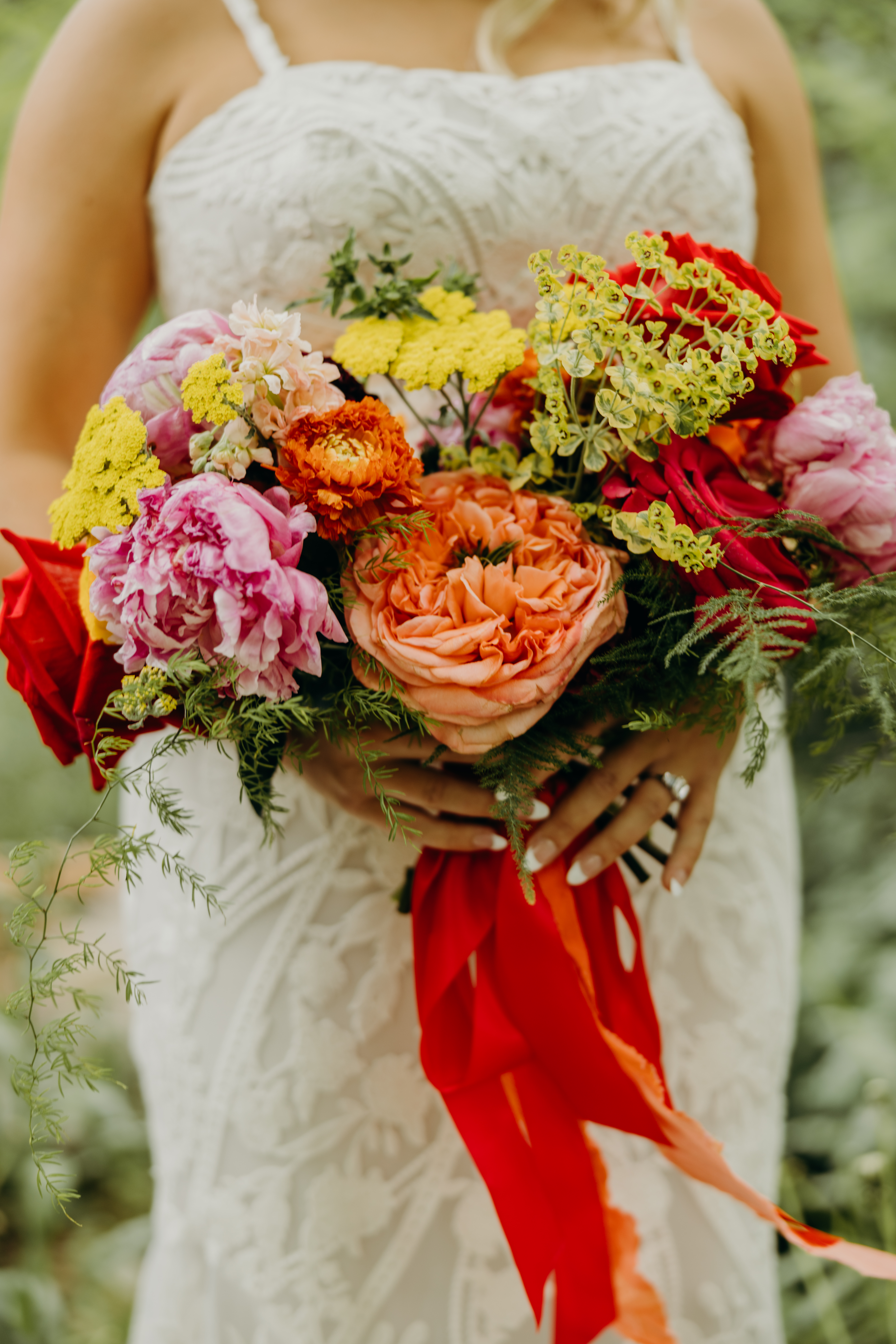 Close-up of a bridal bouquet tied with red ribbon