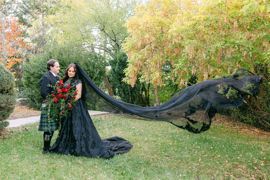 Bride in black with a long train across the lawn
