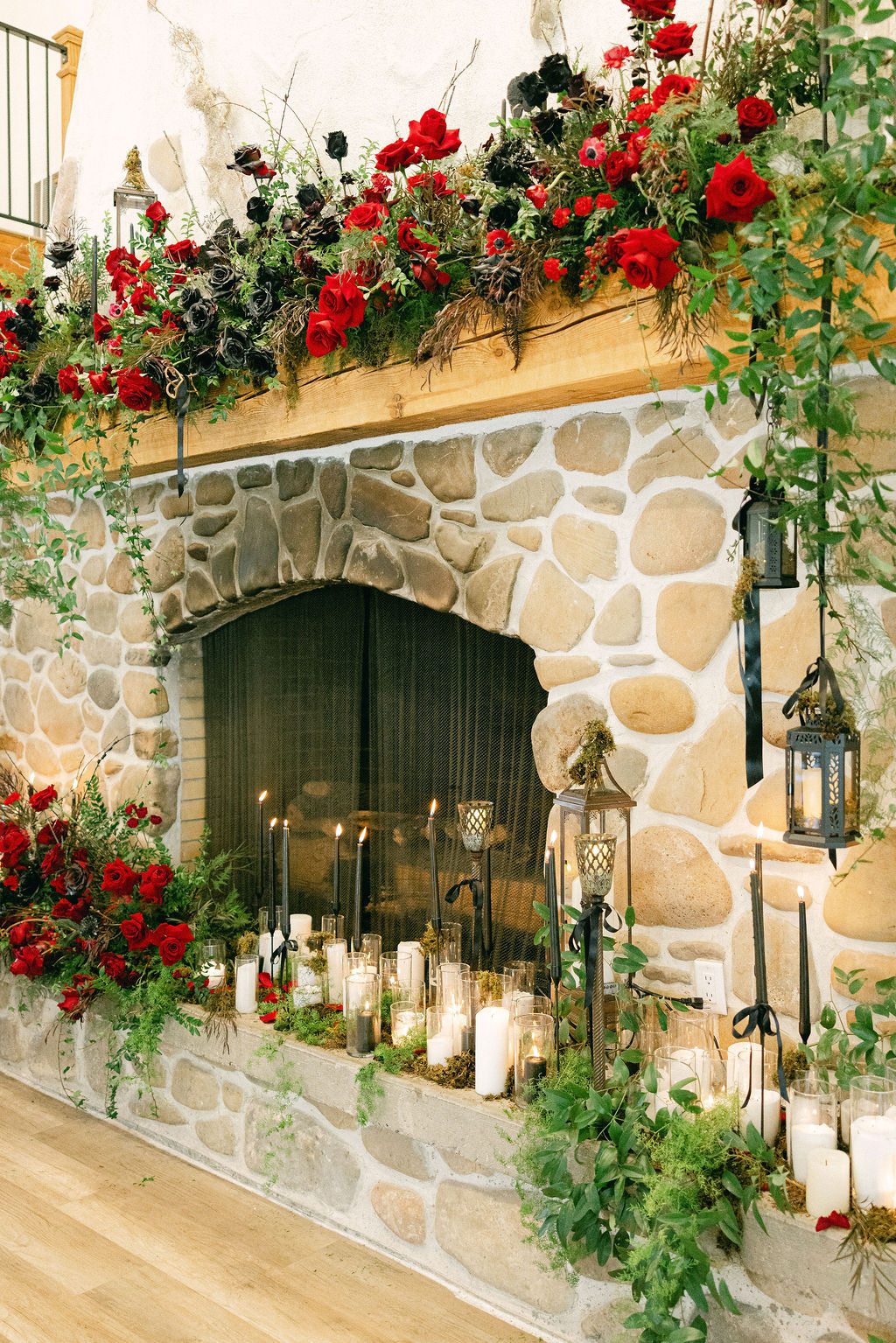 Stone fireplace layered with red roses and candles