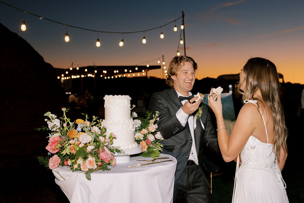 Couple cutting their cake under bistro lights at dusk