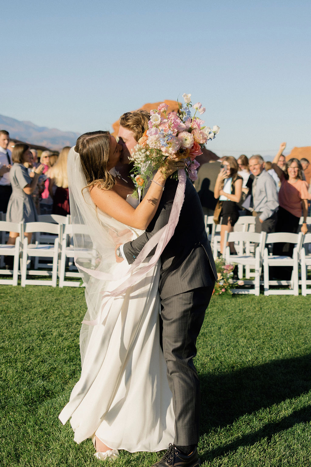 Bride and groom kissing at the end of the aisle