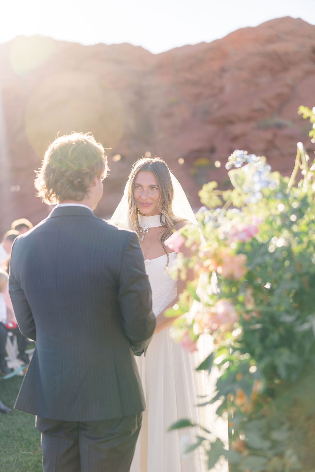 Couple exchanging vows beside a pastel floral column in Southern Utah