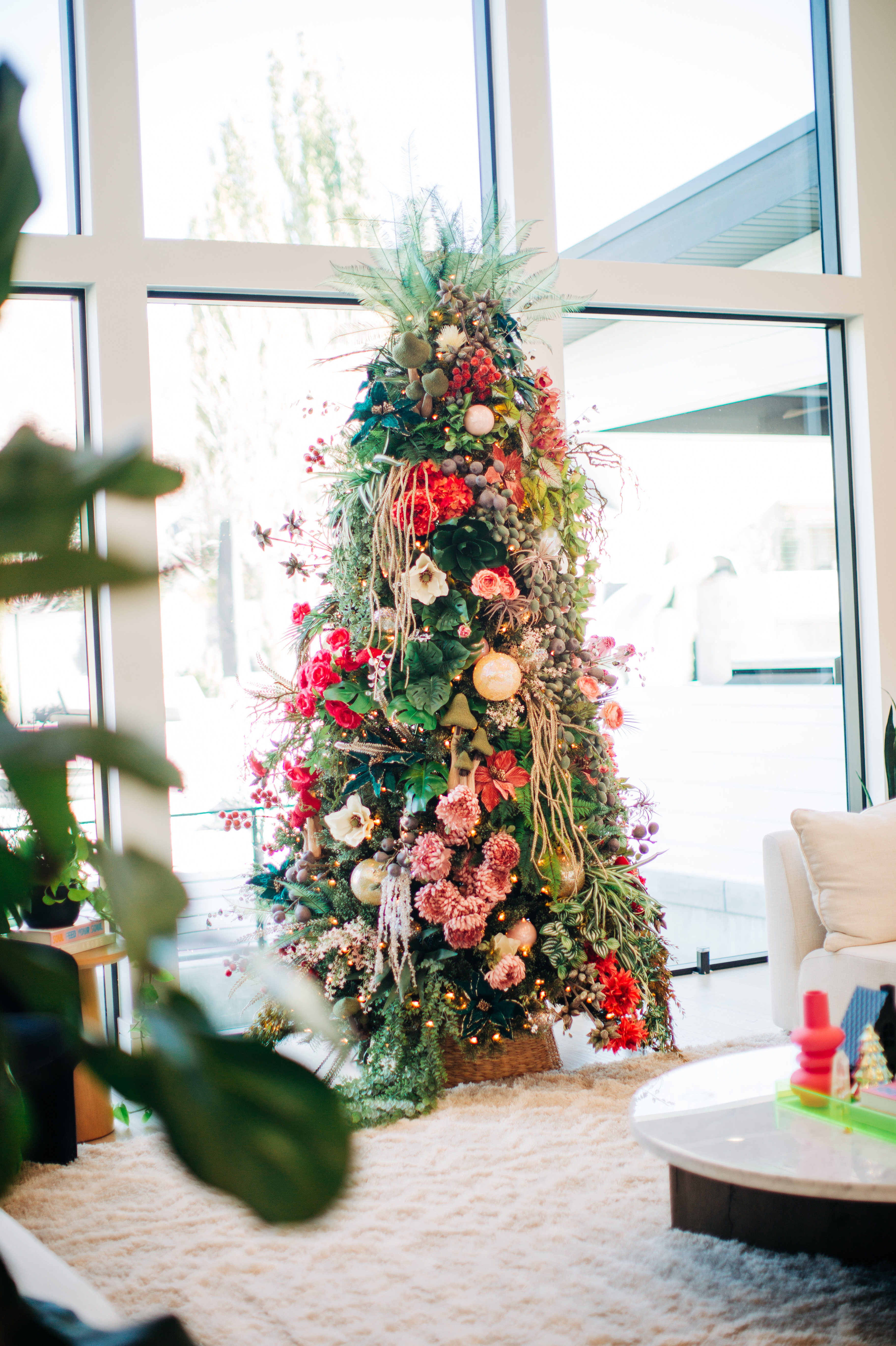 Floor-to-ceiling holiday tree dressed in red and blush florals in a bright modern living room