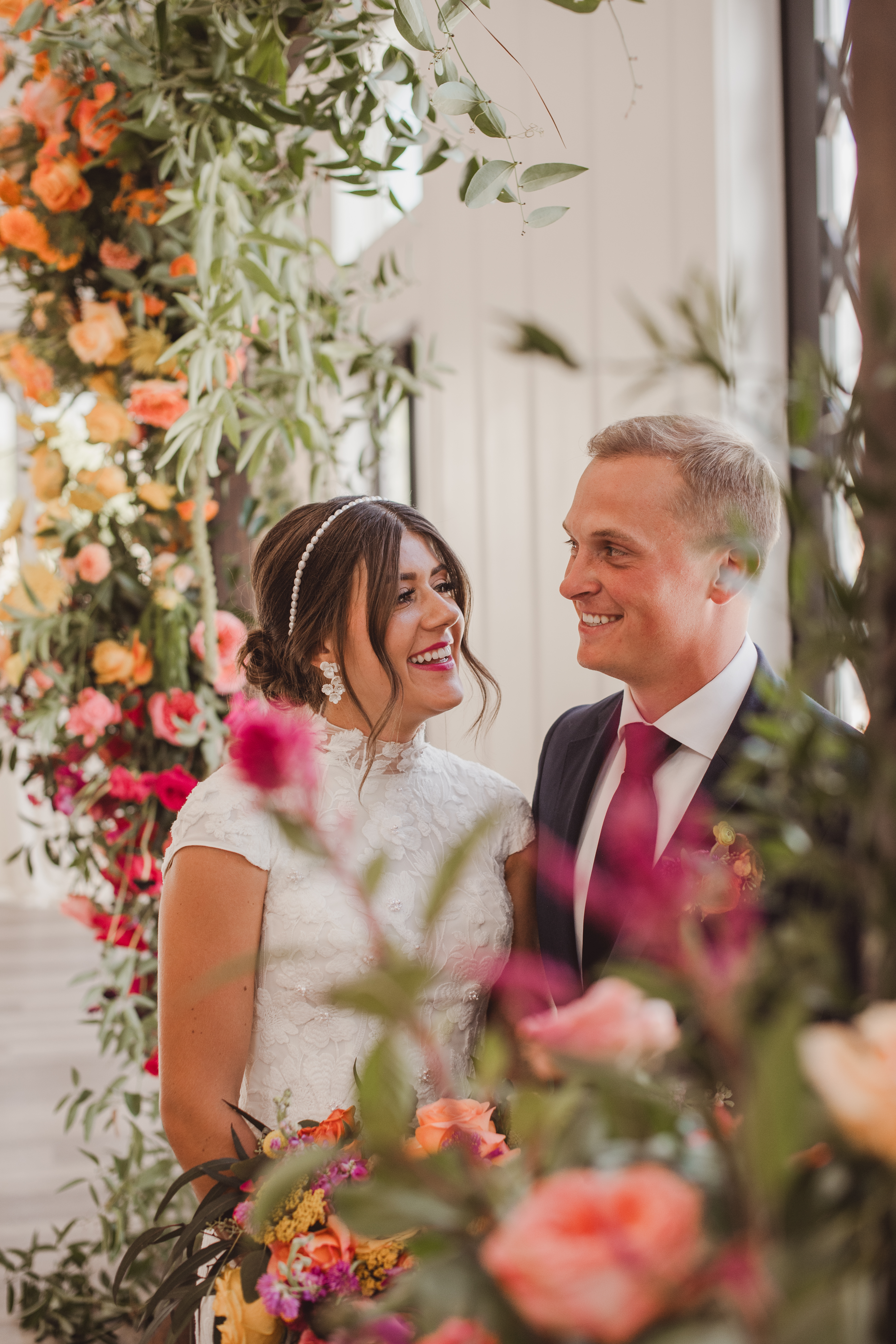 Bride and her father beside a colorful floral arch