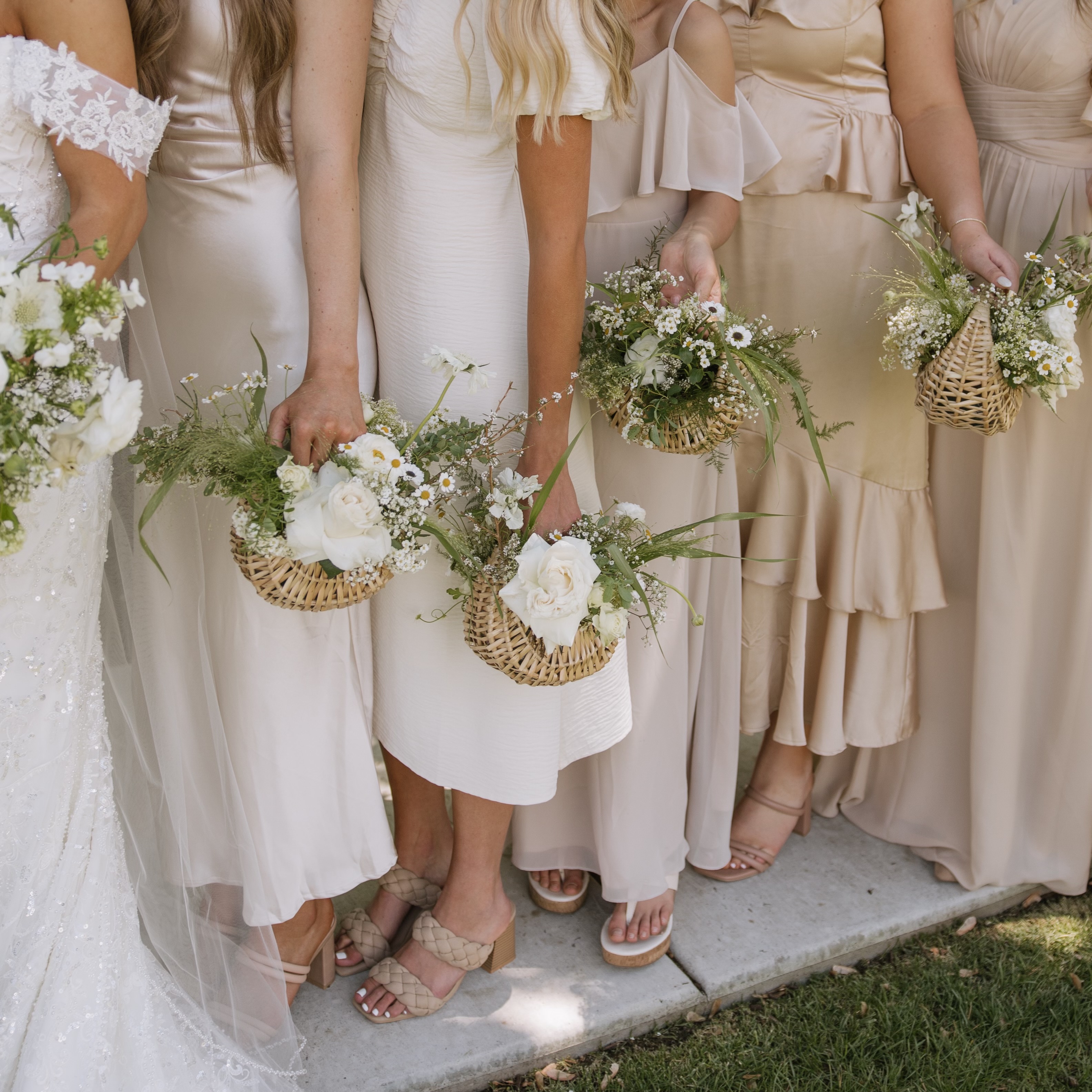 Bridesmaids in neutral tones holding white bouquets