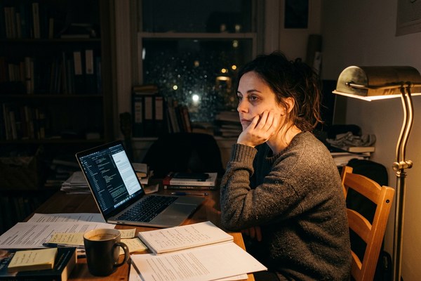 Person at desk late at night staring into the distance